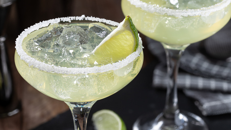 A pale green Margarita in a salt rimmed glass with a slice of lime inside