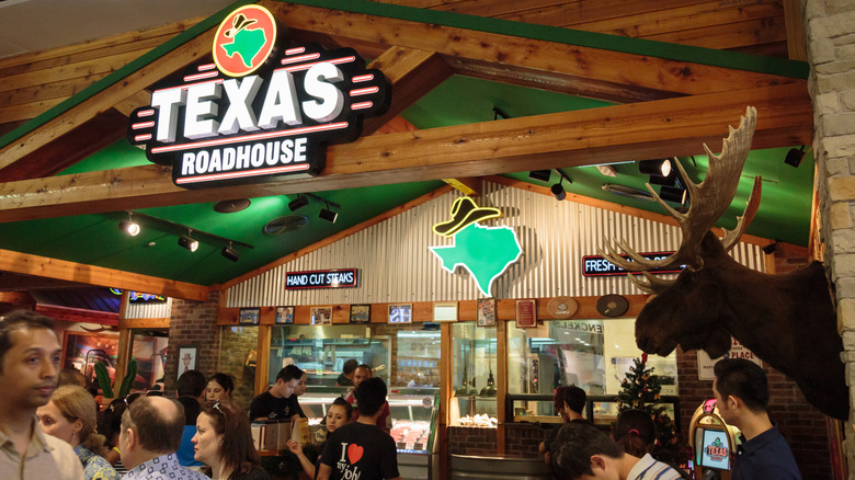 The interior of Texas Roadhouse with a large sign on the beams and a moose head on the wall.