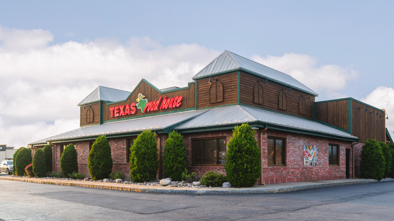 The exterior of a texas roadhouse steakhouse with tall shrubs around it