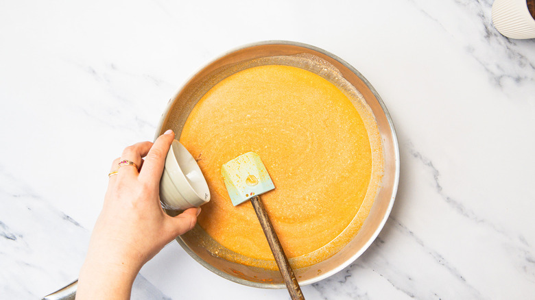 Adding fish sauce to Thai style curry sauce in pan.