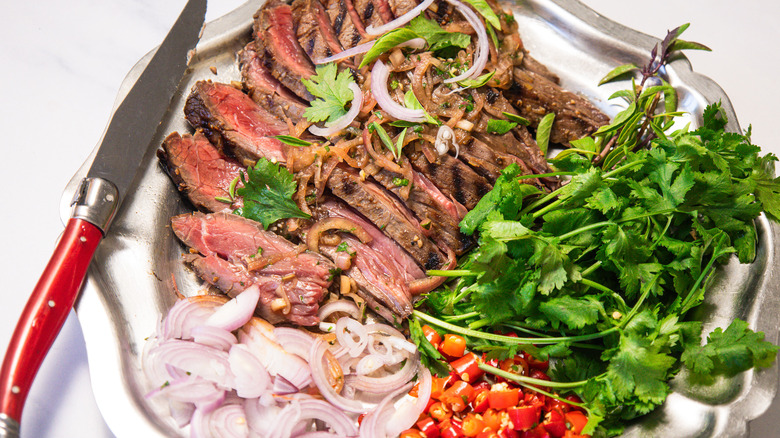 Close up on steak with herbs and toppings with knife