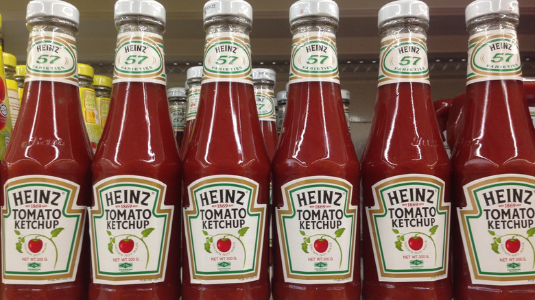 A row of glass Heinz ketchup bottles on a supermarket shelf
