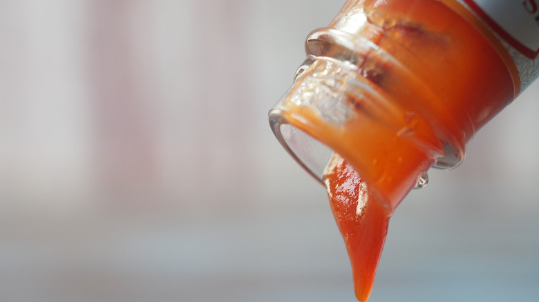Ketchup pouring from the top of a glass bottle