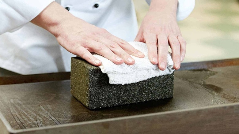 Scrubbing a commercial flat top with grill brick