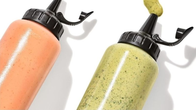 Two squeeze bottles with green and red sauce