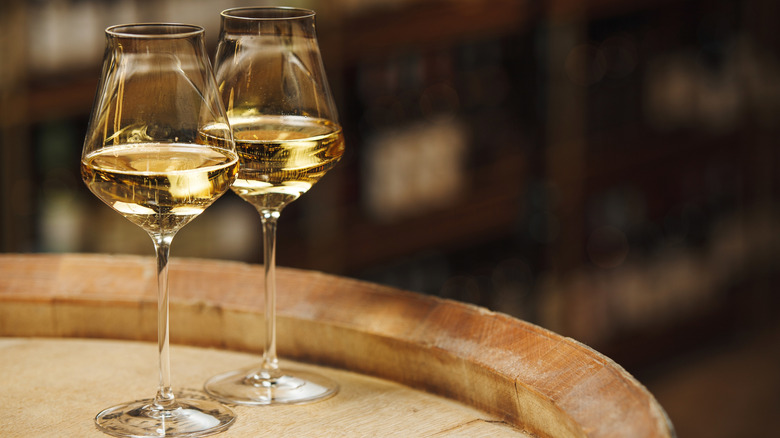 two glasses of white wine on a wooden barrel