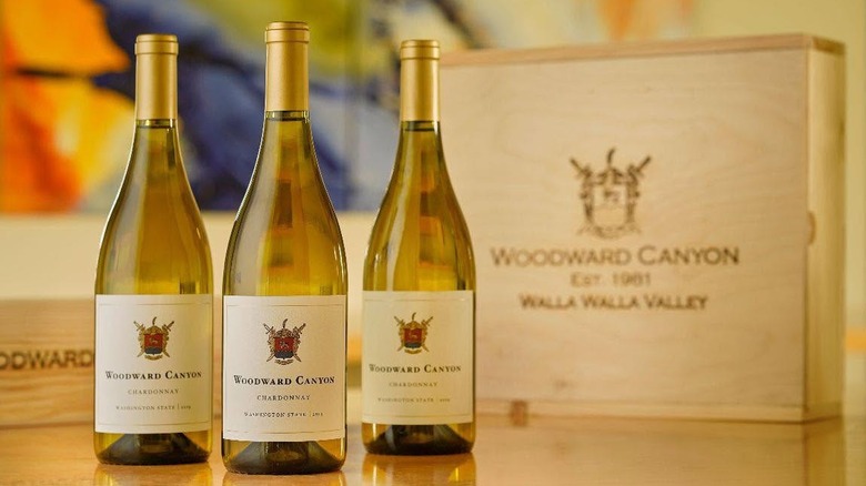 three bottles of white Woodward Canyon Washington State Chardonnay next to wooden wine crate