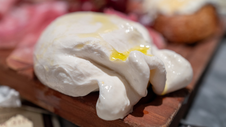 a ball of burrata on a charcuterie board drizzled in olive oil