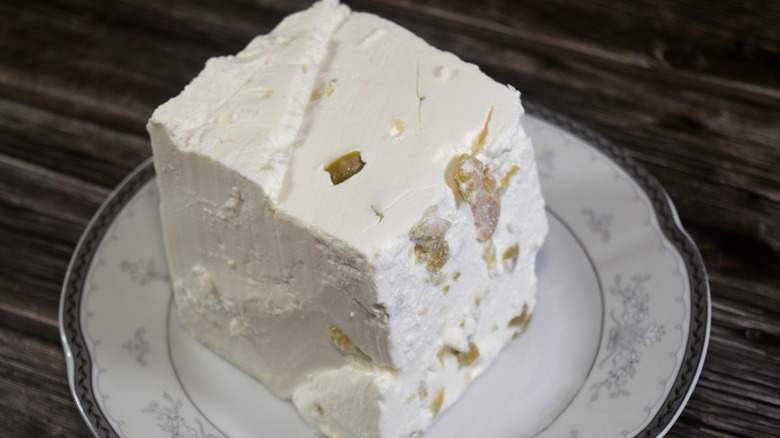 big square of white feat dappled with green olives on a plate