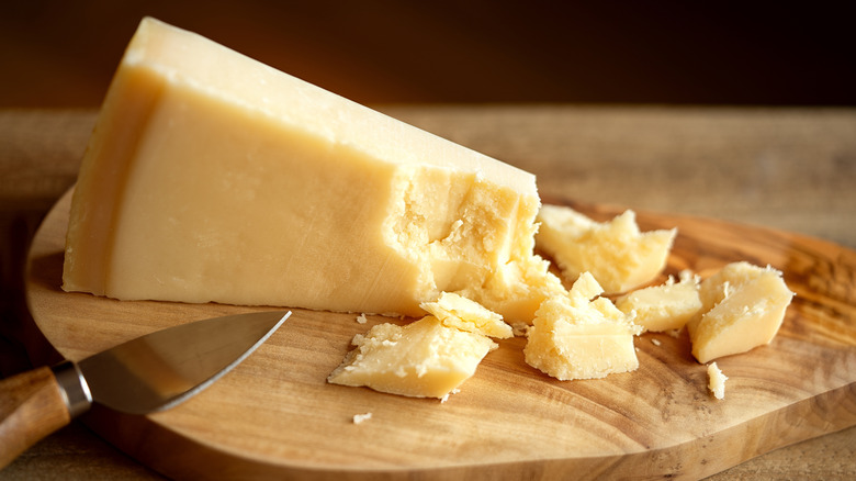 little chunks of Parmigiano Reggiano next to a large hunk of the cheese on board