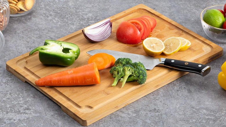 A wide shot of the Empune Extra Large Cutting Board with a knife surrounded by food