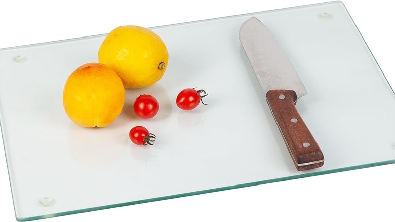 The Murrey Home Glass Cutting Board shown on a blank white background with a knife and fruit on top
