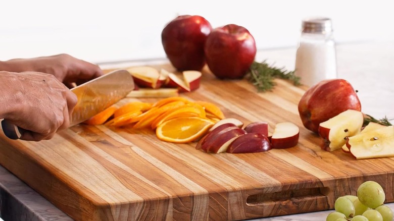 A close up of the Teakhaus Cutting Board being used to chop up fresh fruit
