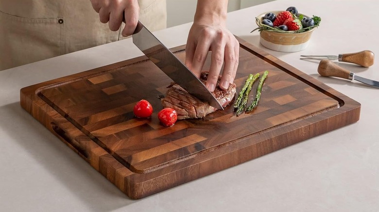 The Thetchry Store Walnut Wood Cutting Board being used to cut cooked meat