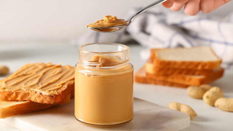 Person's hand taking scoop of nut butter out of jar