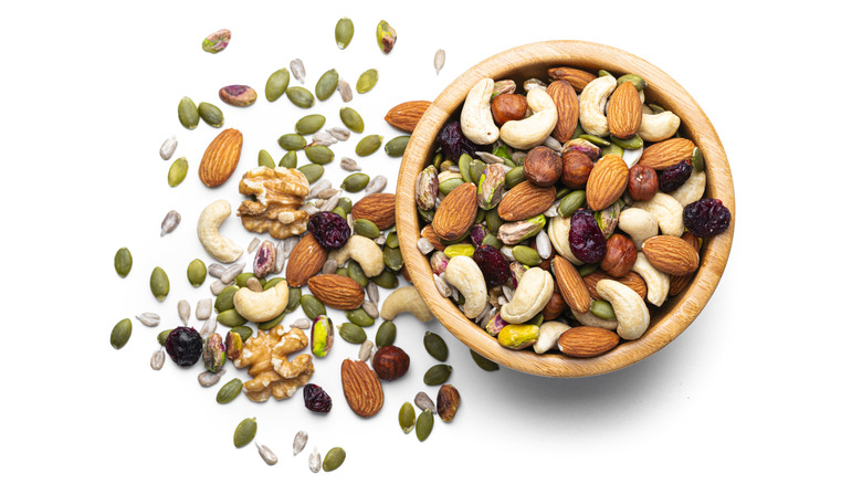 Mixed nuts and seeds spilling out of wooden bowl
