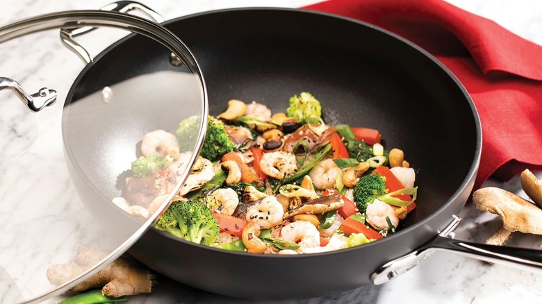 All-Clad HA1 hard anodized nonstick chef's pan and lid with veggies on a marble countertop