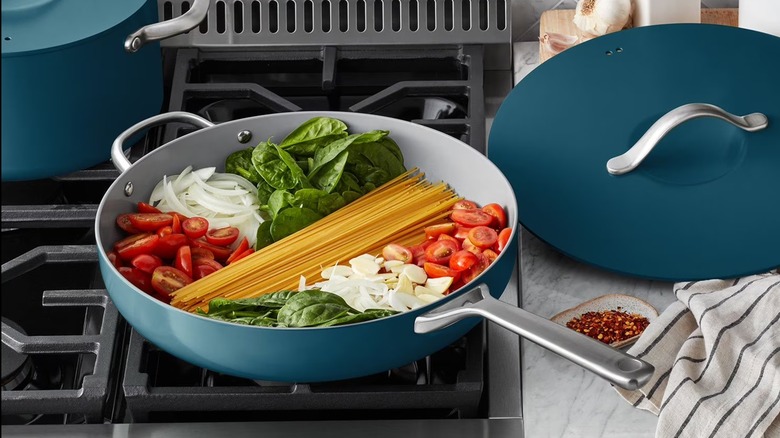 Ingredients in peacock ceramic Member's Mark jumbo cooker on stovetop with lid to the side