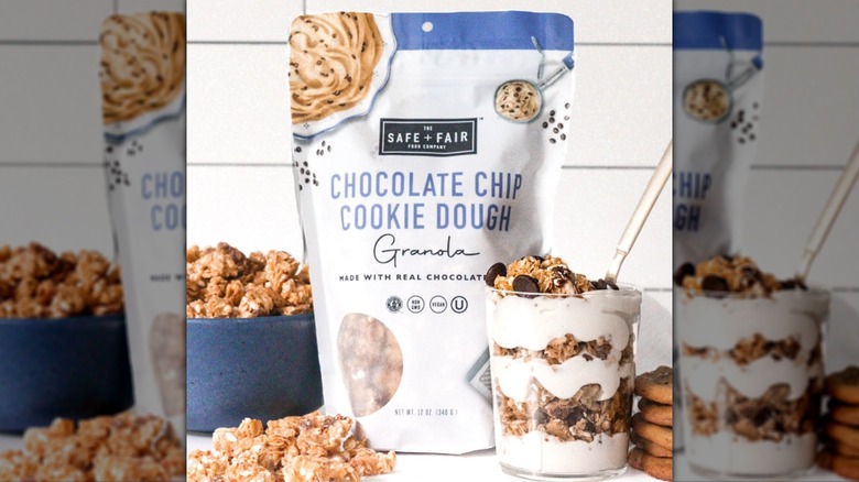 Package of Safe + Fair Chocolate Chip Cookie Dough Granola, next to breakfast parfait in dessert glass