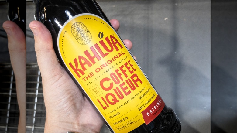 A hand holding a bottle of Kahlúa liquor