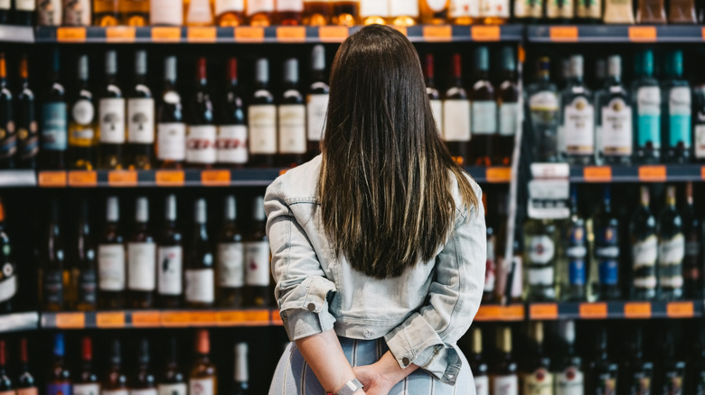 woman standing in front of wall of wine