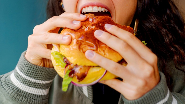 Close-up of a person holding and eating a burger