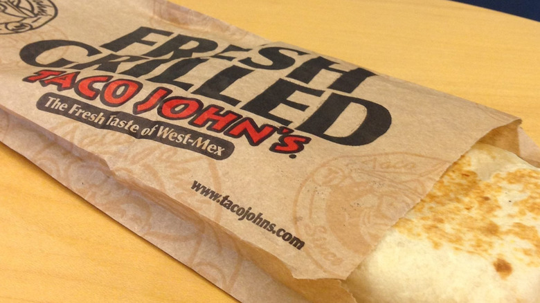 A Taco John's grilled stuffed taco in a paper wrapper