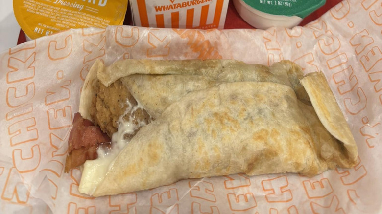 A big Ranch wrap on paper in front of some Whataburger fries and sauces