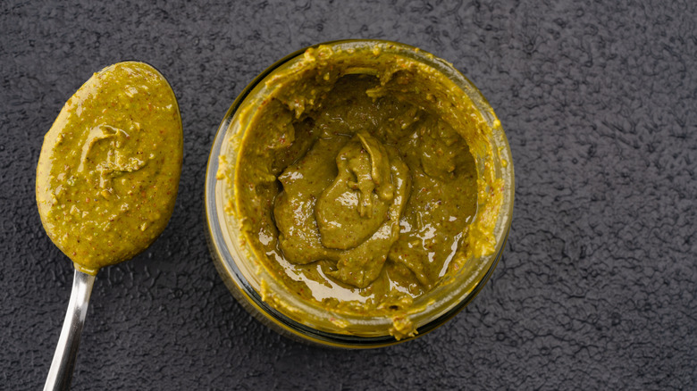 Jar of pistachio butter next to spoonful of pistachio butter