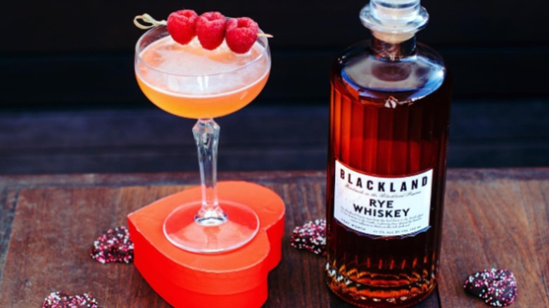 Bottle of Blackland Rye Whiskey with cocktail and chocolate hearts