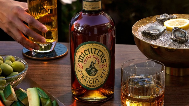 Bottle of Michter's Straight Rye with glass in foreground and background with oysters