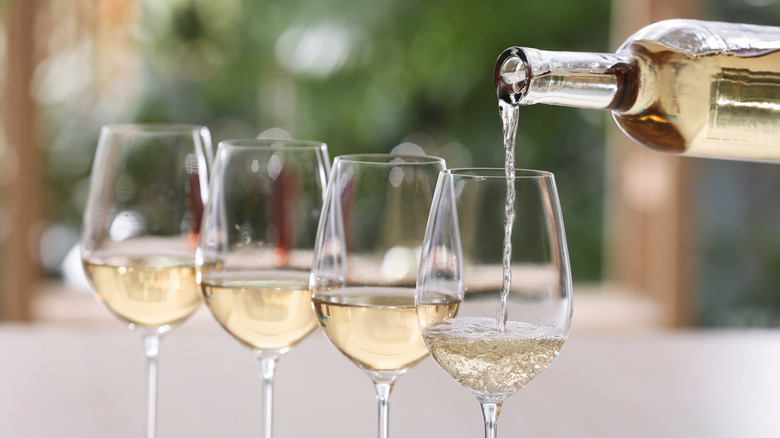 pouring white wine into multiple glasses