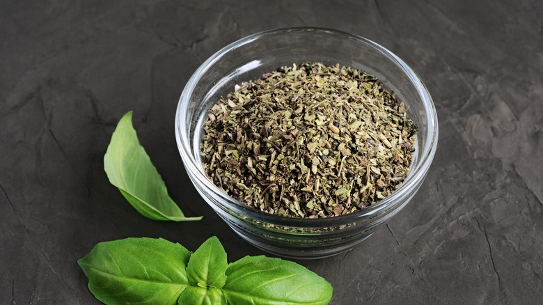 Bowl of dried basil with fresh basil in background