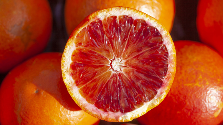 Blood orange sliced open with whole oranges in the background