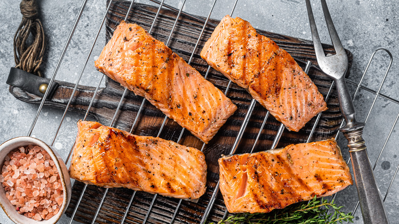 Grilled salmon filets on wire rack with serving fork and pink rock salt.