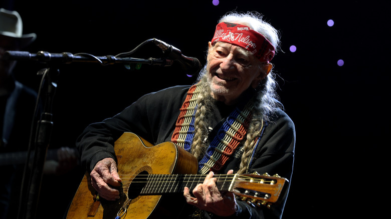 Willie Nelson performing wearing his signature bandana