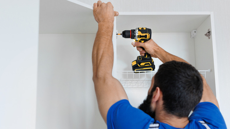 Man attaching a cabinet door with an electric screwdriver