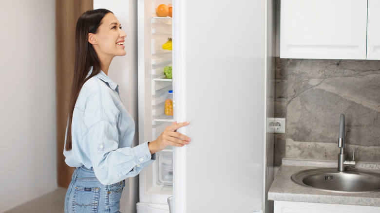 Lady looking inside of fridge while standing in kitchen