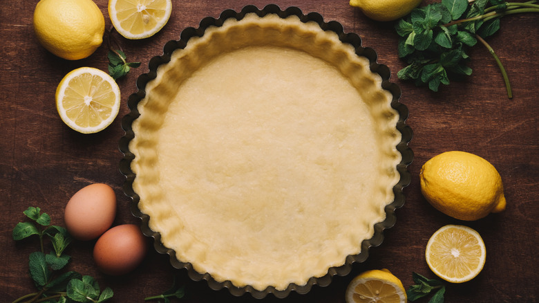 crust in tart tin surrounded by lemons and eggs