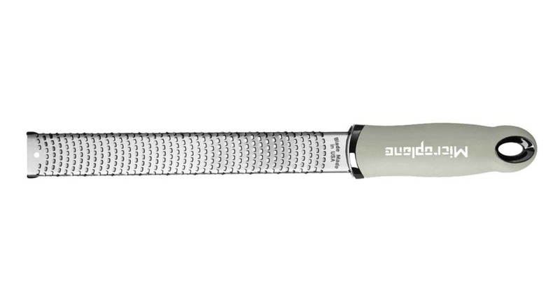 A Microplane grater and zester with gray handle against white background