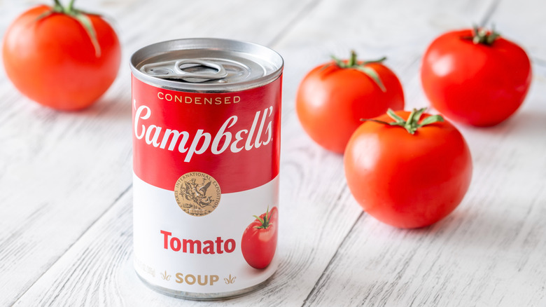 Can of Campbell's soup on wooden surface with tomatoes
