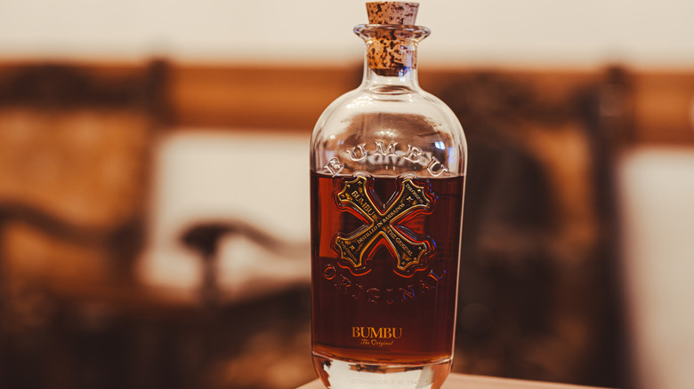 Open bottle of Bumbo Original rum against blurry background.