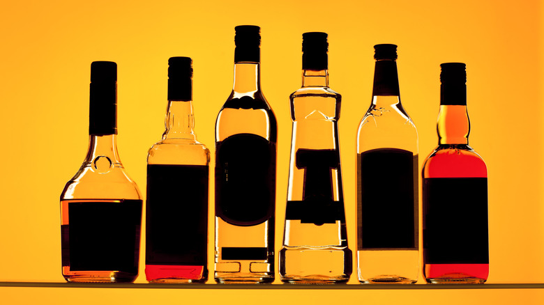 Backlit liquor bottles silhouetted against orange background.
