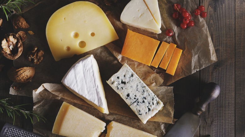 Various cheeses on a cheese board beside berries and a cheese knife