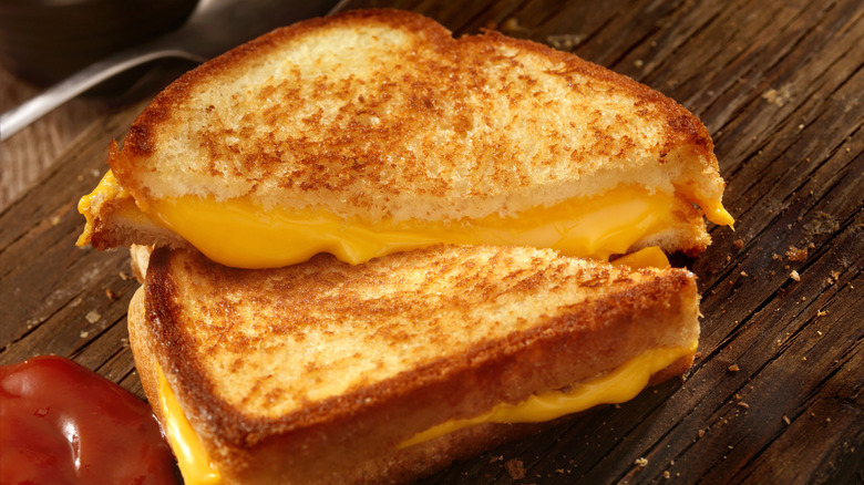 A sliced grilled cheese sandwich on a wooden board