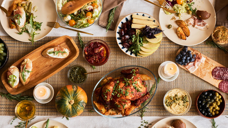 A top view of a Thanksgiving dinner table with an array of dishes on pretty serving trays and platters