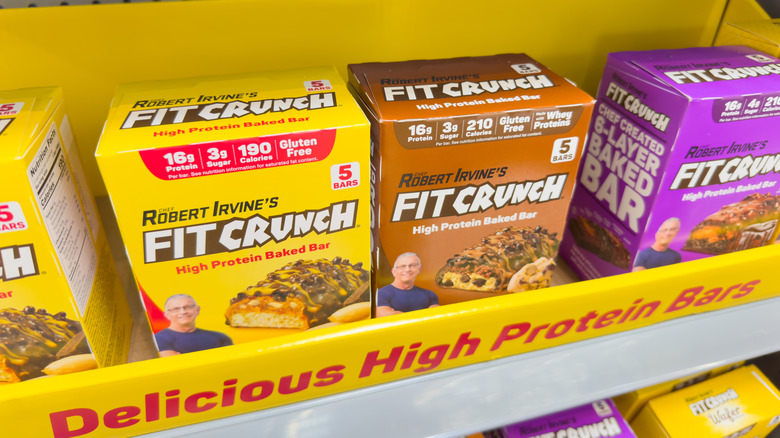 Three boxes of various FitCrunch Bars on a grocery store shelf