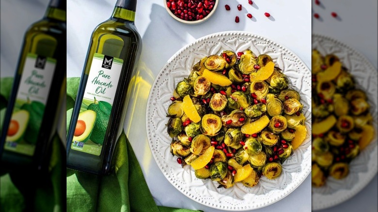 Glass bottle of avocado oil beside salad