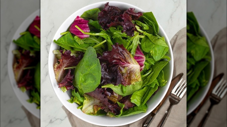 Bowl of spring mix with napkin, fork, and knife adjacent