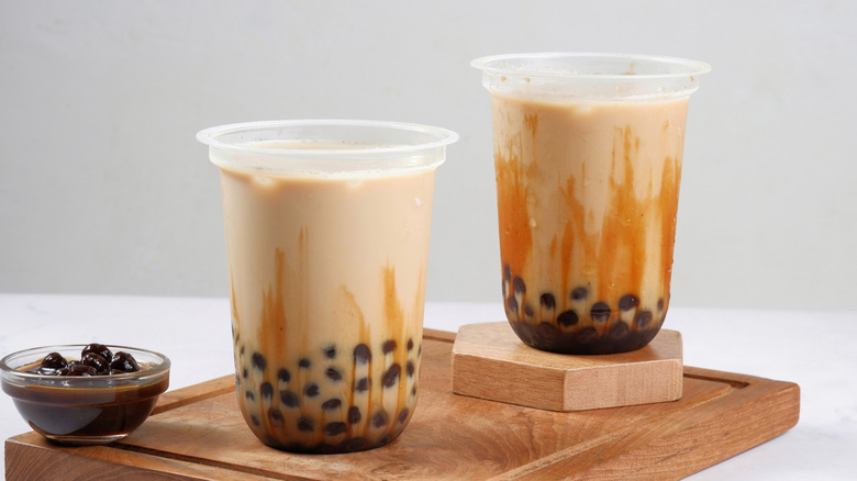 Two glasses of boba tea with extra boba on the side